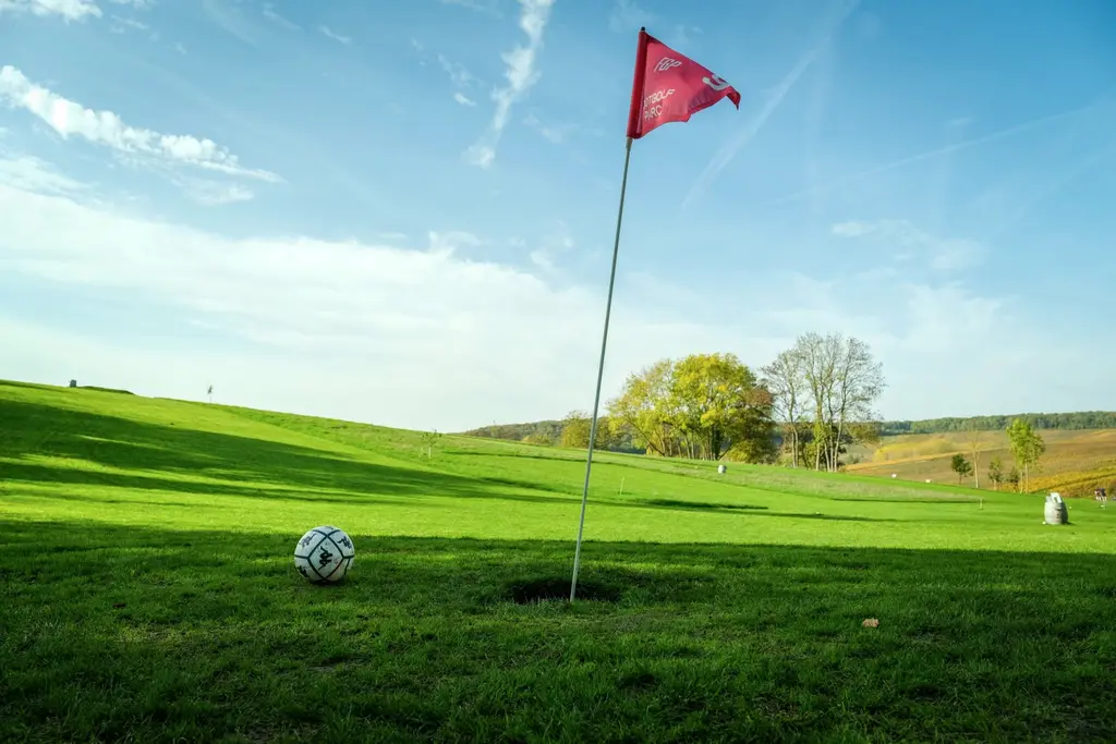 Un drapeau rouge et un ballon sur le green d'un parcours de Footgolf